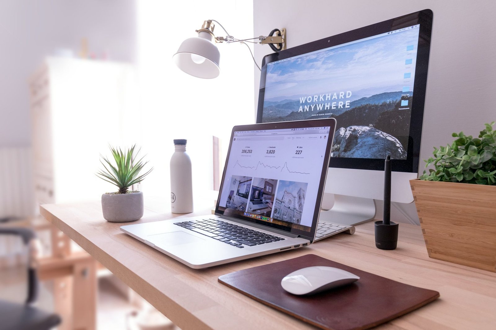 A bright desk with a laptop and a desktop computer